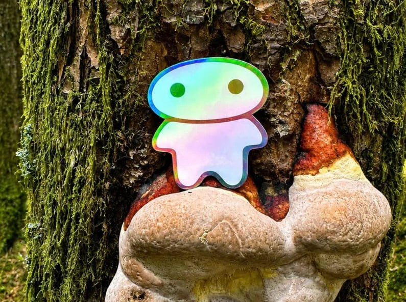 lil alien bae sticker sitting on a mushroom stump on a tree