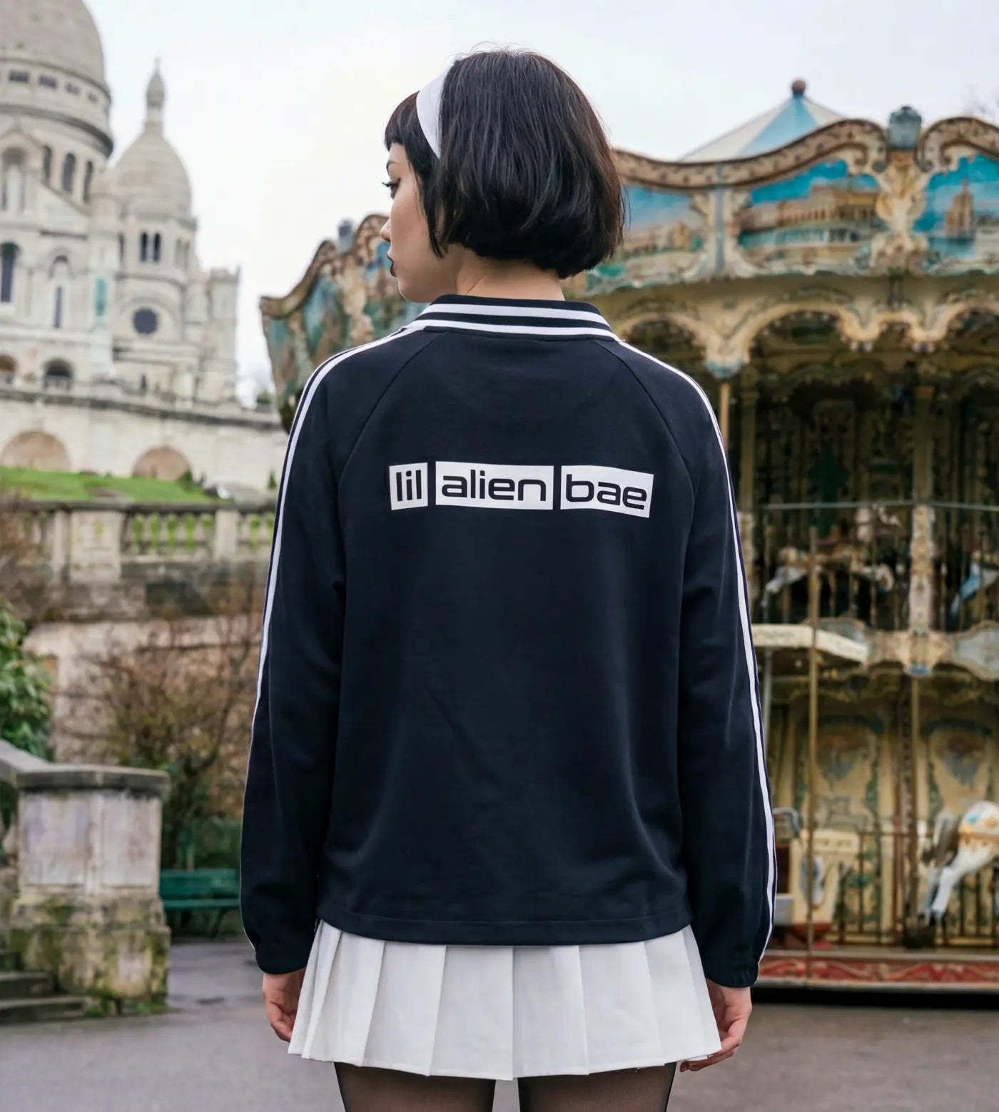 Model wears a black lapel collar pullover featuring a Lil Alien Bae back graphic and styled outfit. 