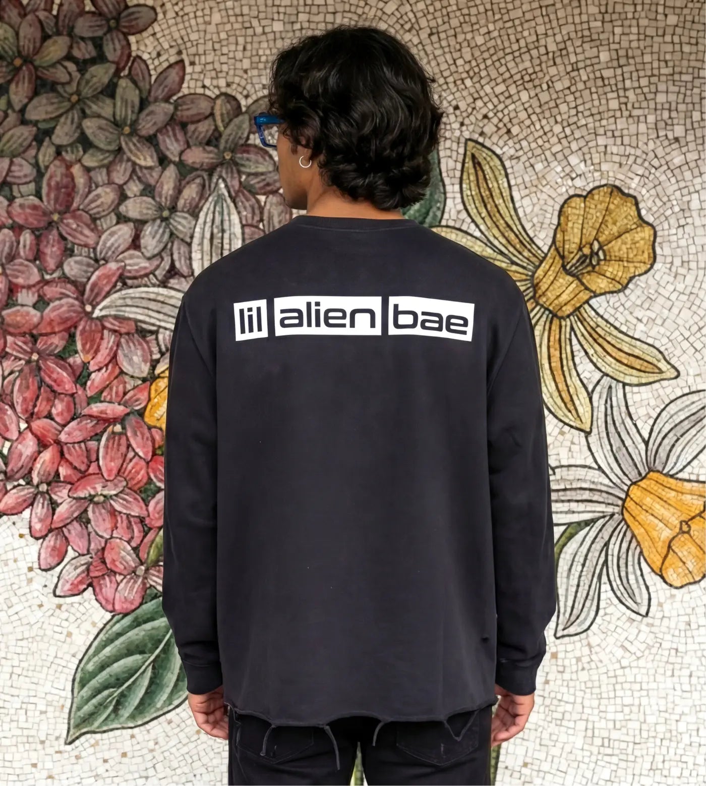 Model wears a black vintage washed long sleeve shirt with raw edge hem and Lil Alien Bae back graphic.  