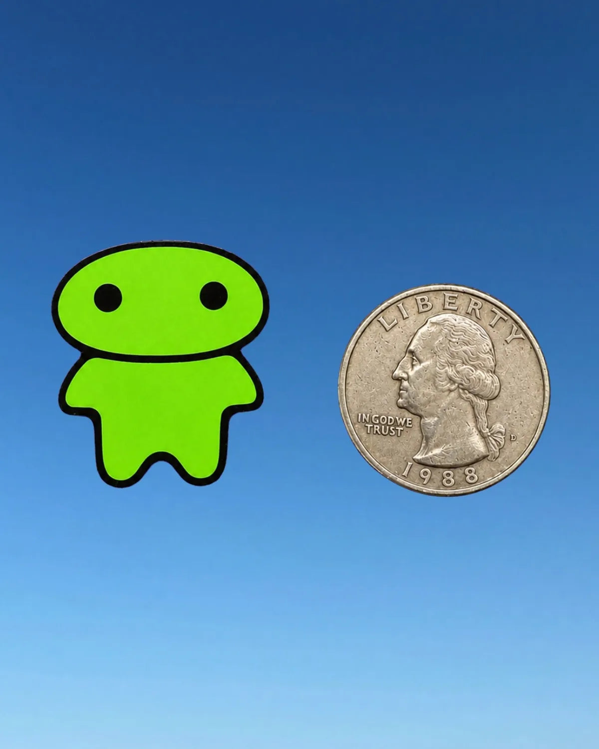 A bright green lil alien bae sticker or decal with black outlines is shown next to a US quarter coin on a blue gradient background to indicate size.