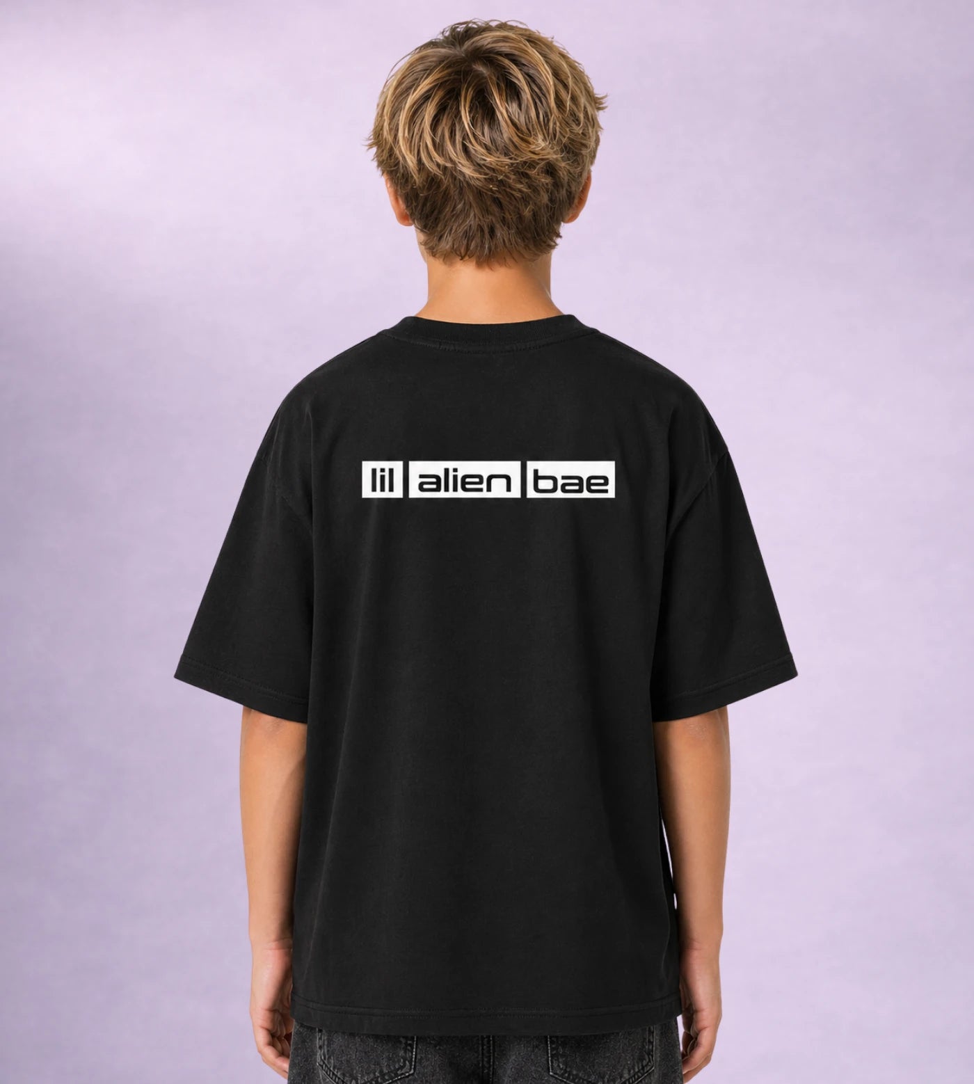 Model wears a youth black cotton T-shirt featuring a Lil Alien Bae back graphic.