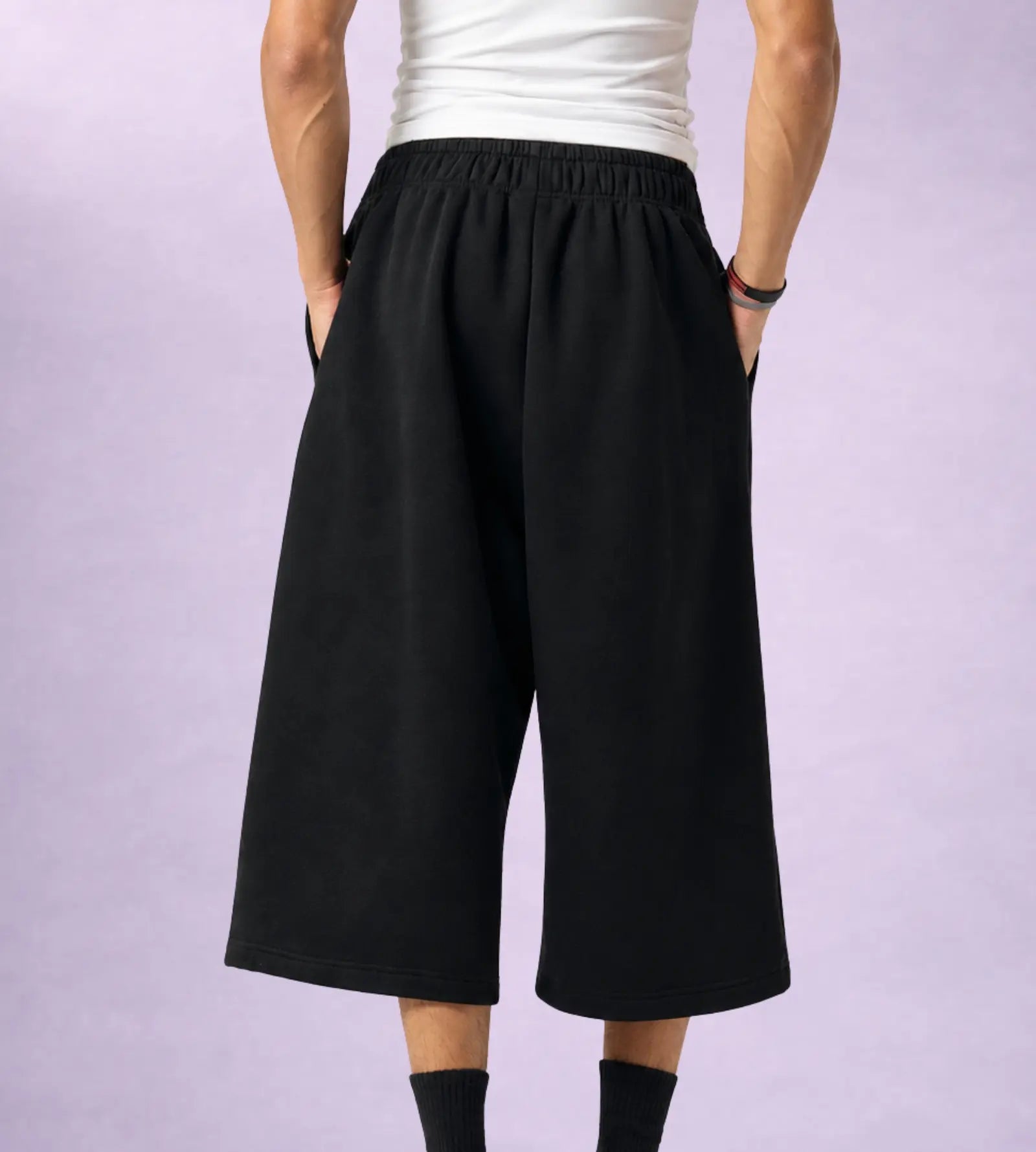 Person wearing black wide-leg pants and a white top on a light purple background