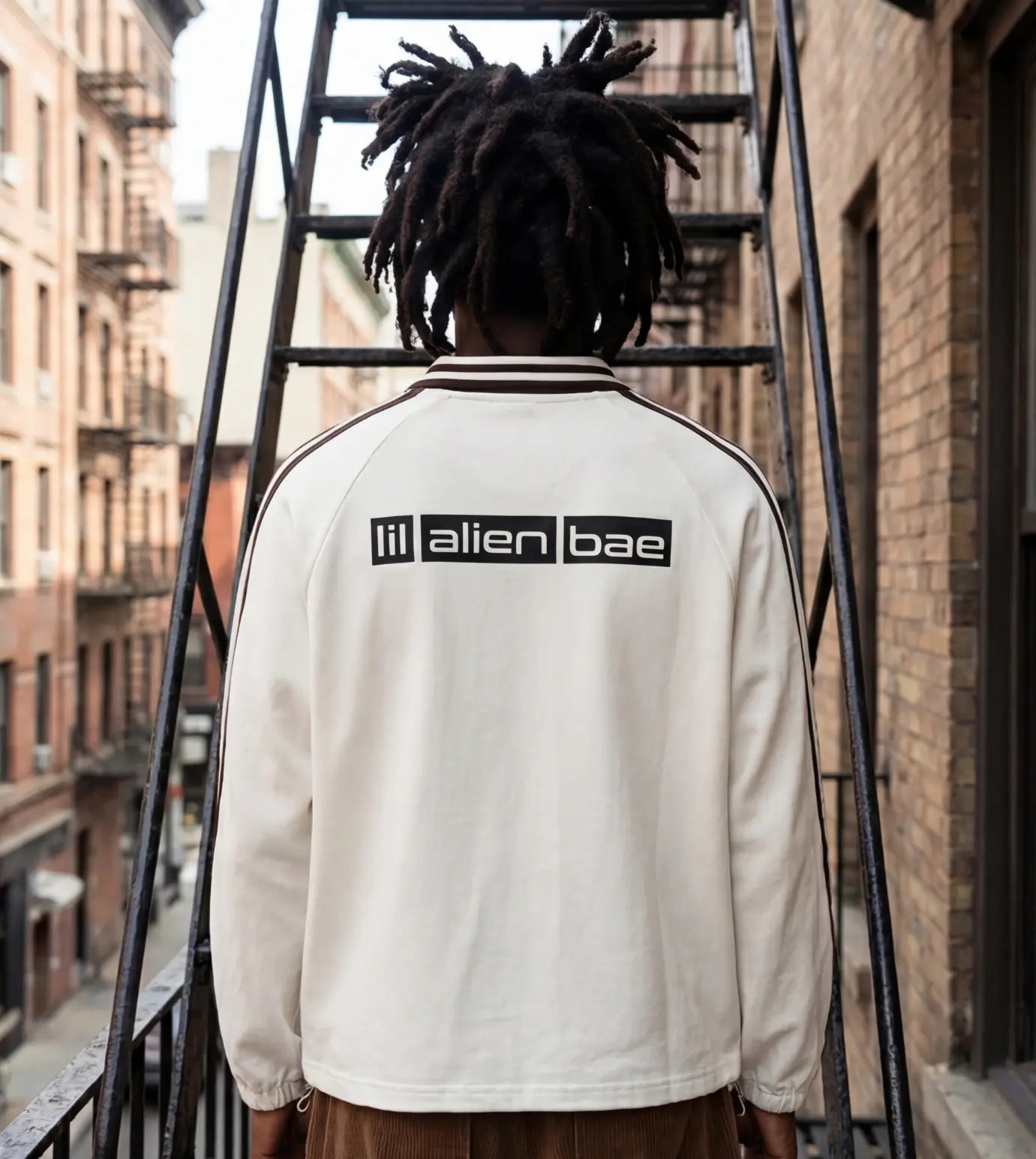 Model wears an off white lapel collar pullover featuring a Lil Alien Bae back graphic.