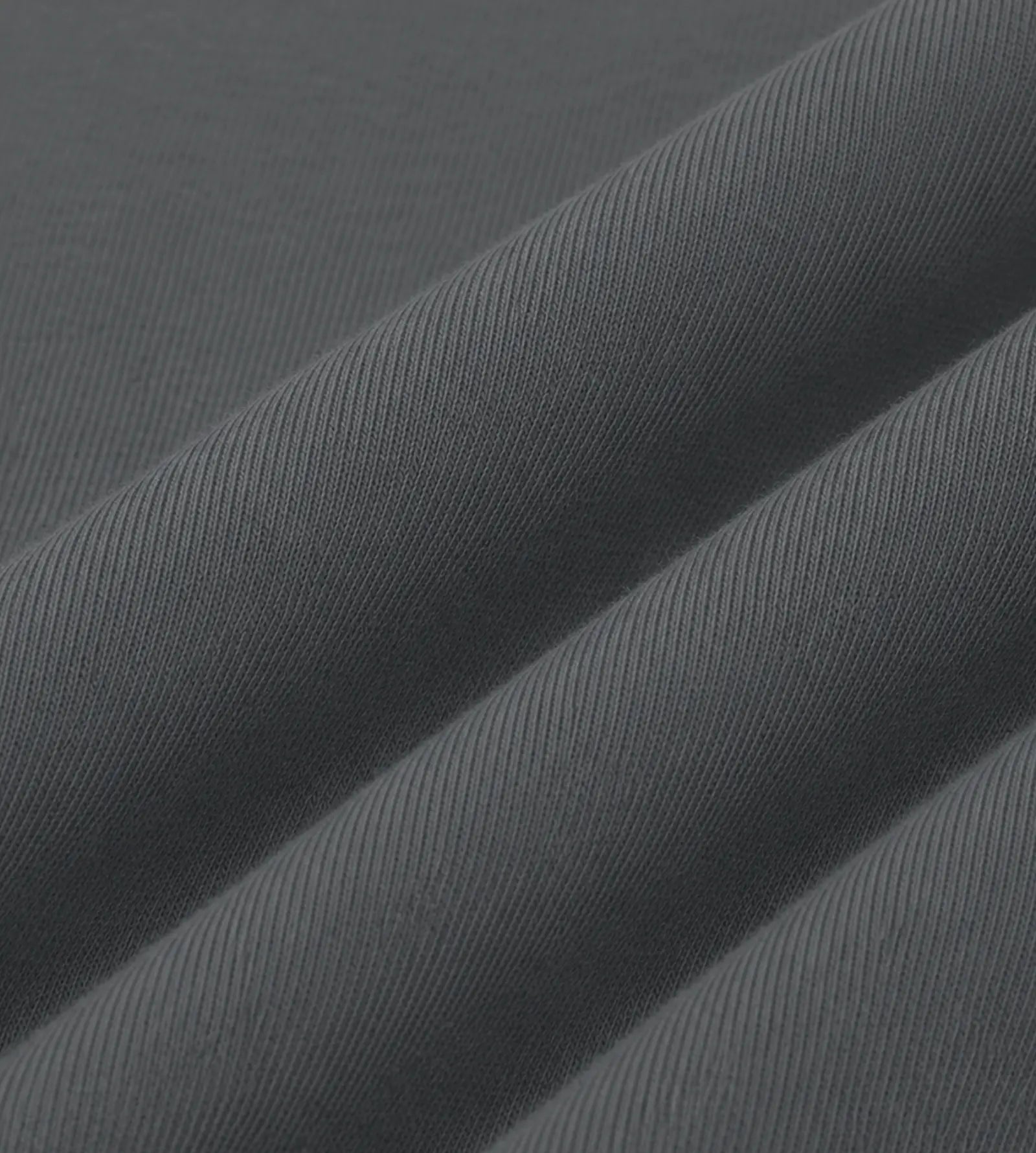 A close-up of dark gray ribbed fabric with diagonal folds showing the texture and weave.