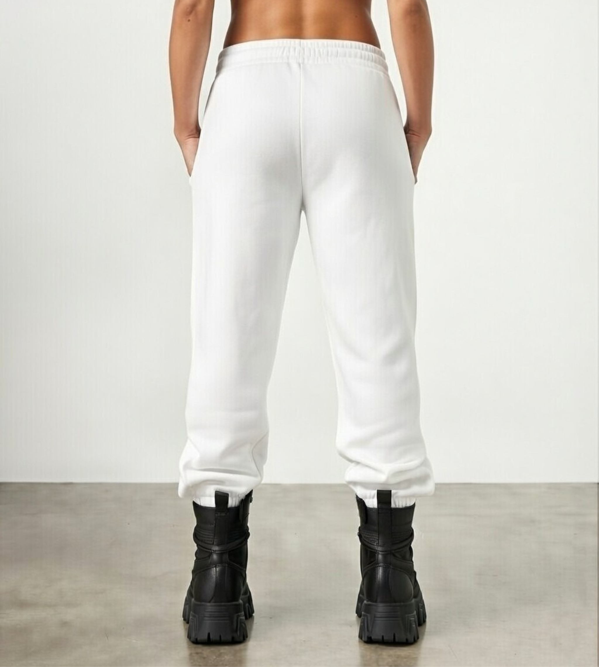 Female model wears white, fleece joggers, back view. 