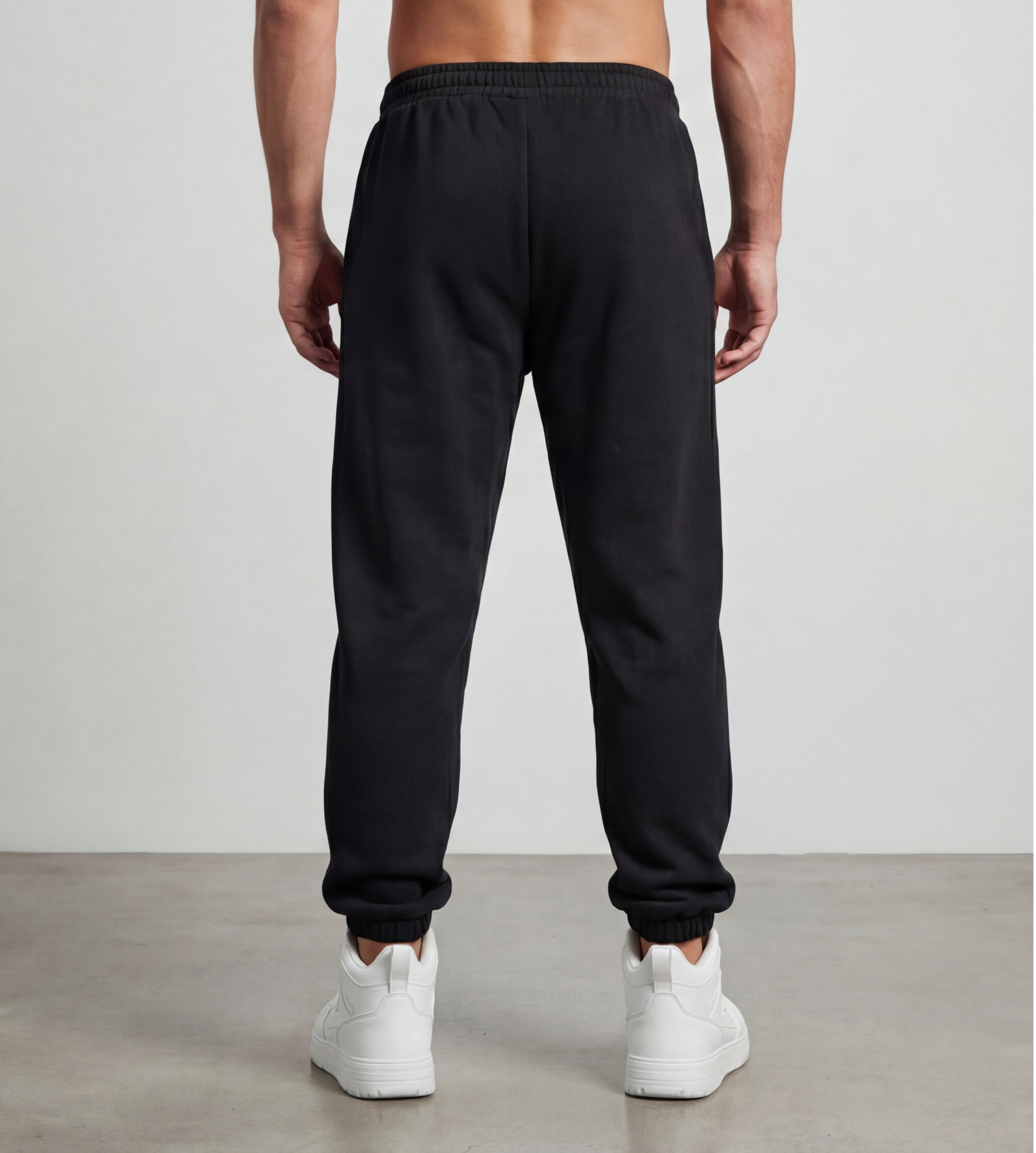 Male model wears black, fleece jogger from the back.