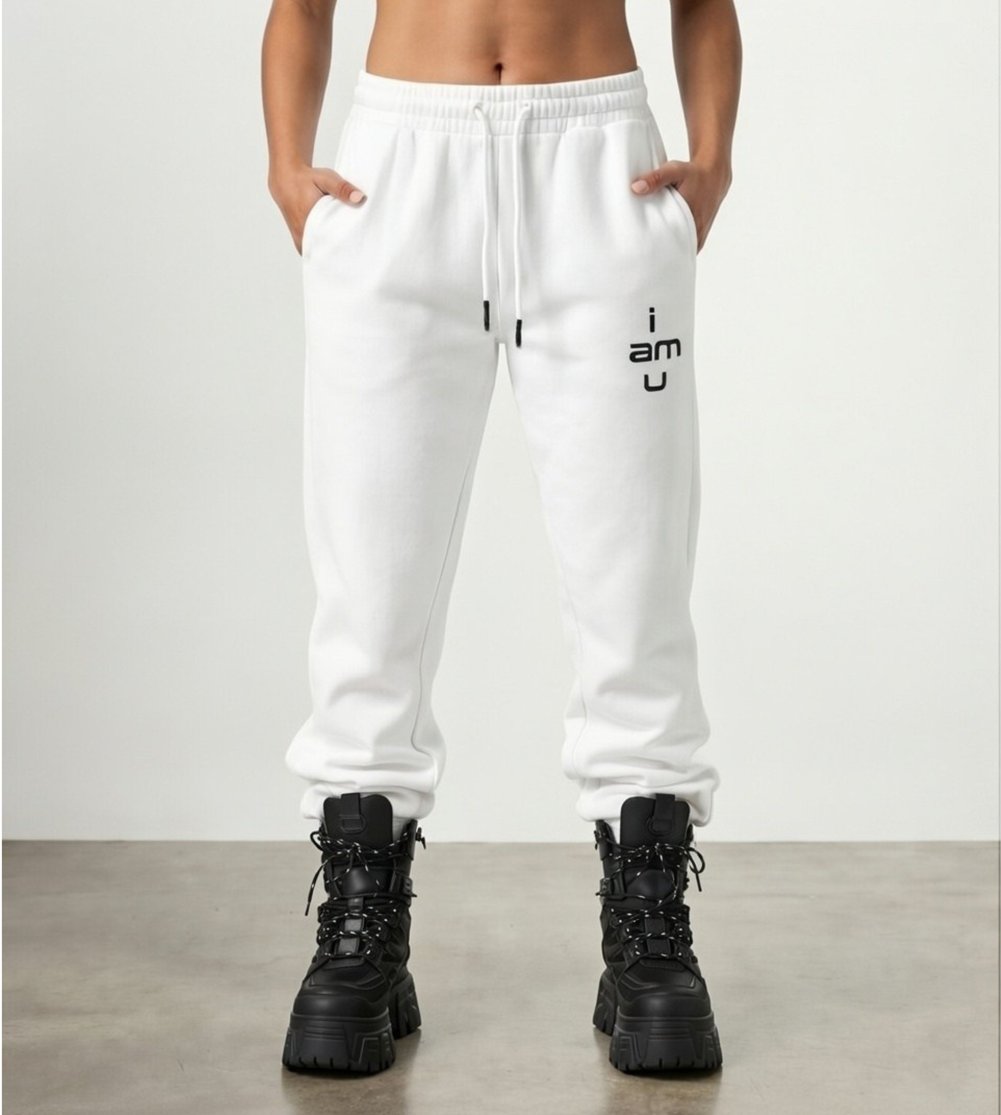 Model wears white, fleece joggers featuring "i am u" slogan under left pocket styled with black boots.  